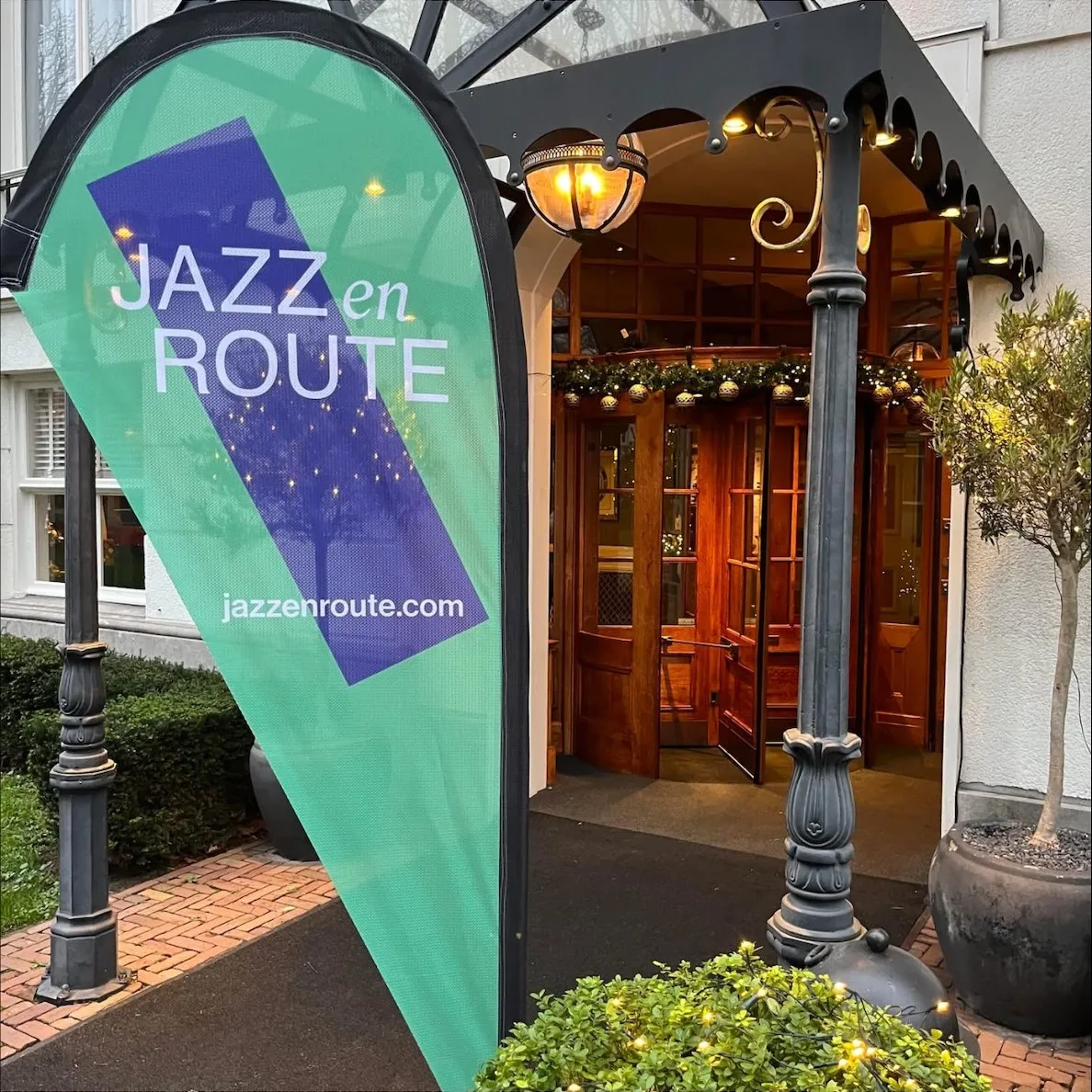 Ingang van het Carlton Ambassador Hotel met een Jazz en Route vlag