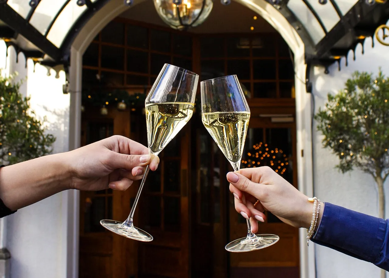 Two clinking glasses in front of the Carlton Ambassador entrance, in a festive Christmas atmosphere