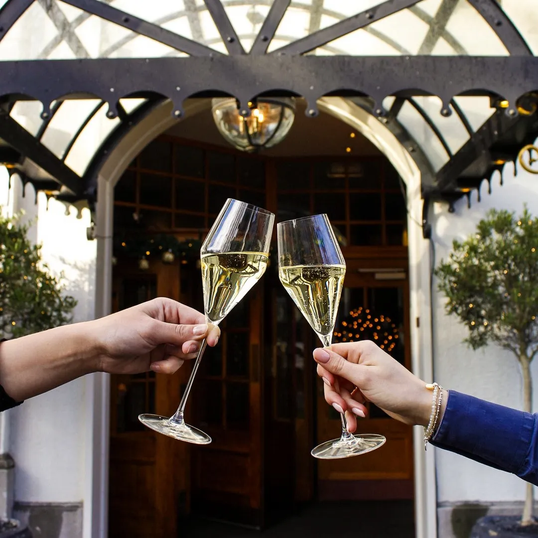 Klinkende champagneglazen bij de ingang van Carlton Ambassador